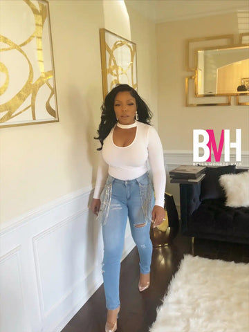 A person wearing a white long-sleeve top and light blue jeans with heels.