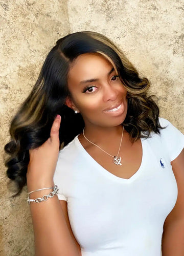 A smiling person wearing a white v-neck shirt and silver jewelry.