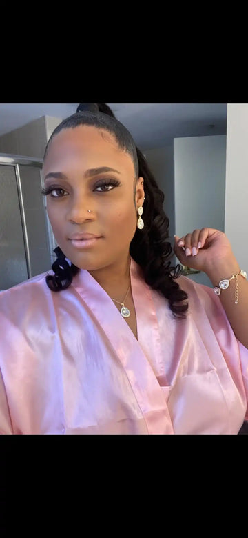 A selfie showing someone wearing a pink satin blouse and delicate jewelry.