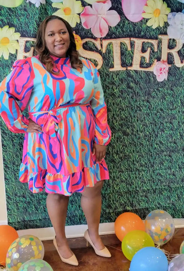 A vibrant pink, blue and orange ruffled dress with long sleeves.